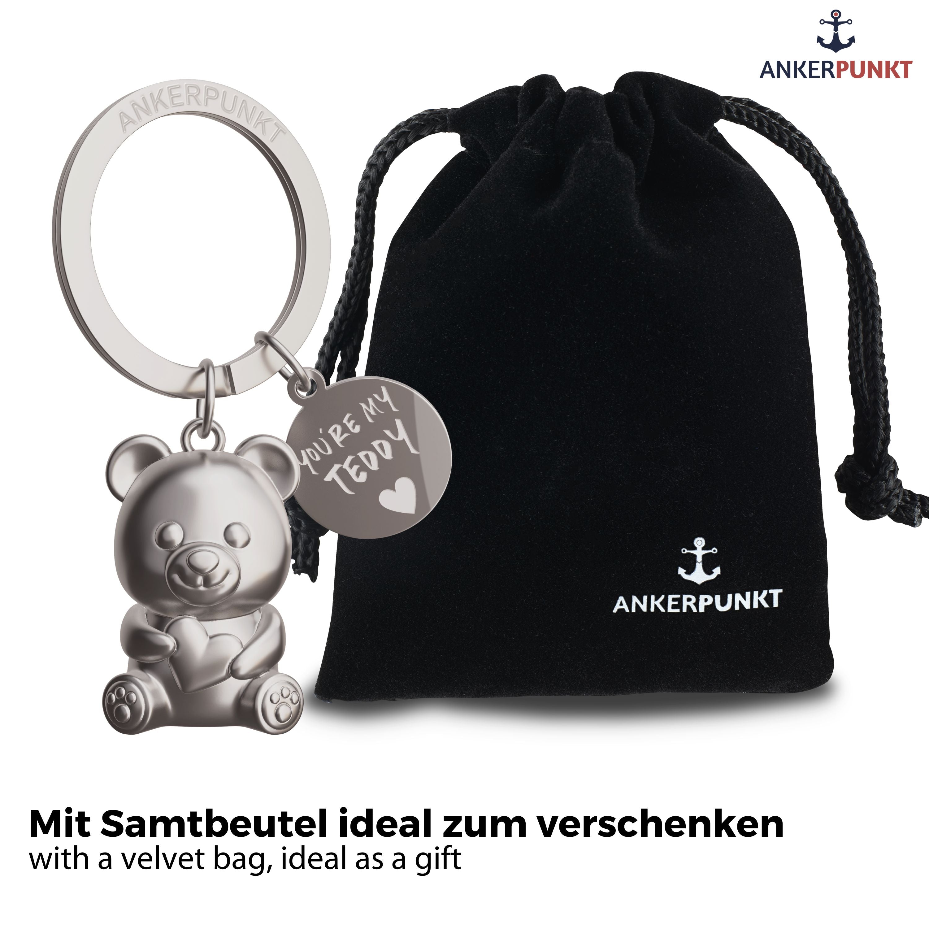 Teddybär Schlüsselanhänger in silbermatt mit Anhängerplättchen mit Gravur "You're my Teddy", daneben ein Samtbeutel mit Ankerpunkt-Logo