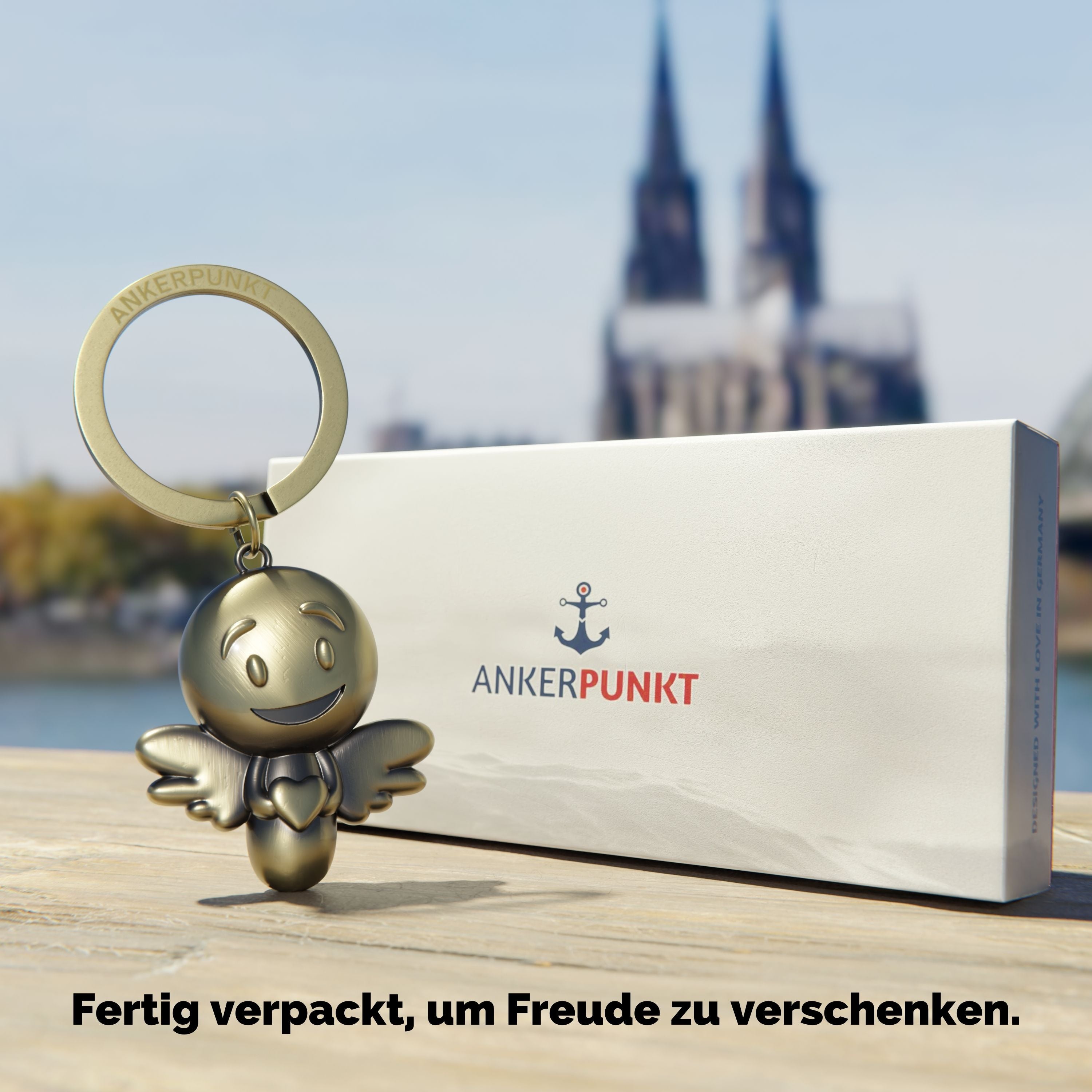 Schlüsselanhänger Lovely gold vintage mit Verpackung am Rhein, im Hintergrund ist der Kölner Dom zu sehen