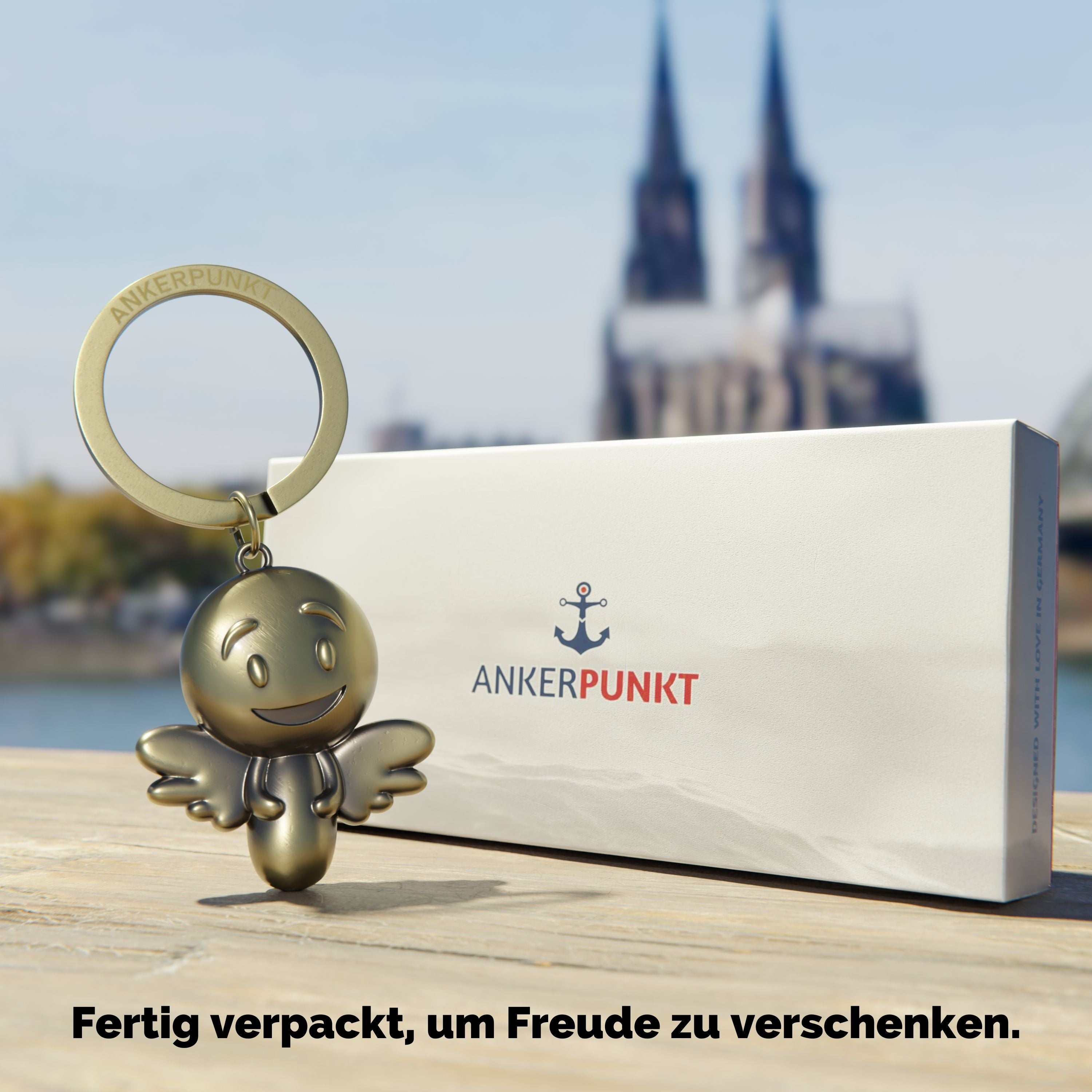 Schlüsselanhänger Engel gold vintage mit Verpackung am Rhein, im Hintergrund ist der Kölner Dom zu sehen