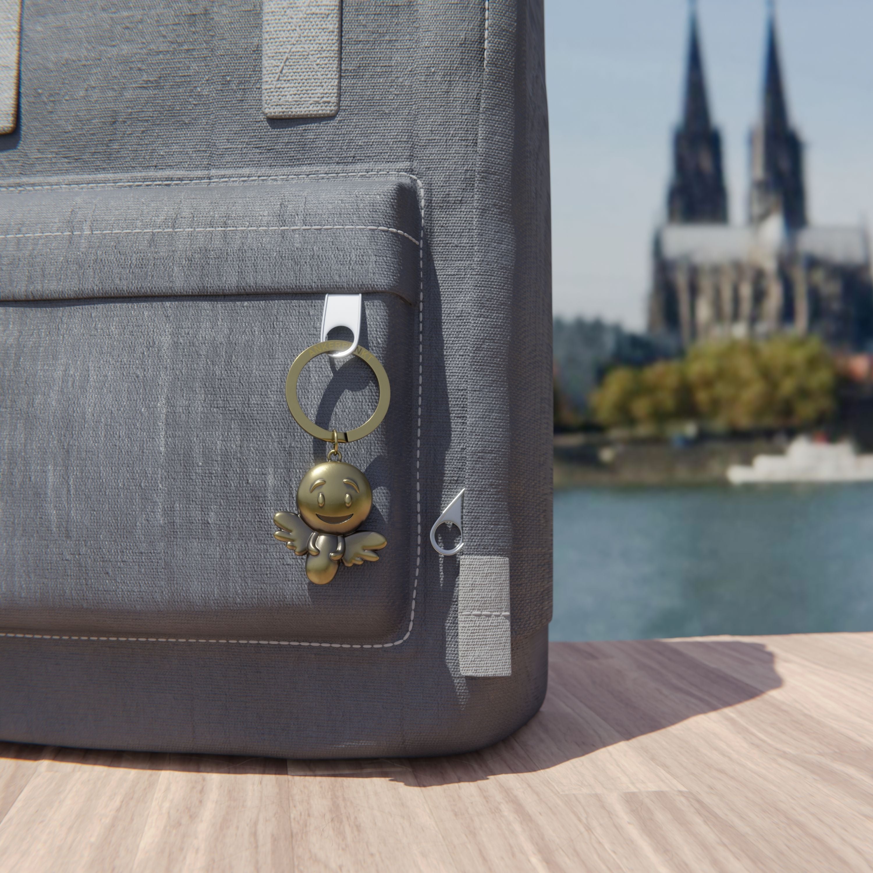 Schlüsselanhänger Engel gold vintage mit Rucksack am Rhein, im Hintergrund ist der Kölner Dom zu sehen