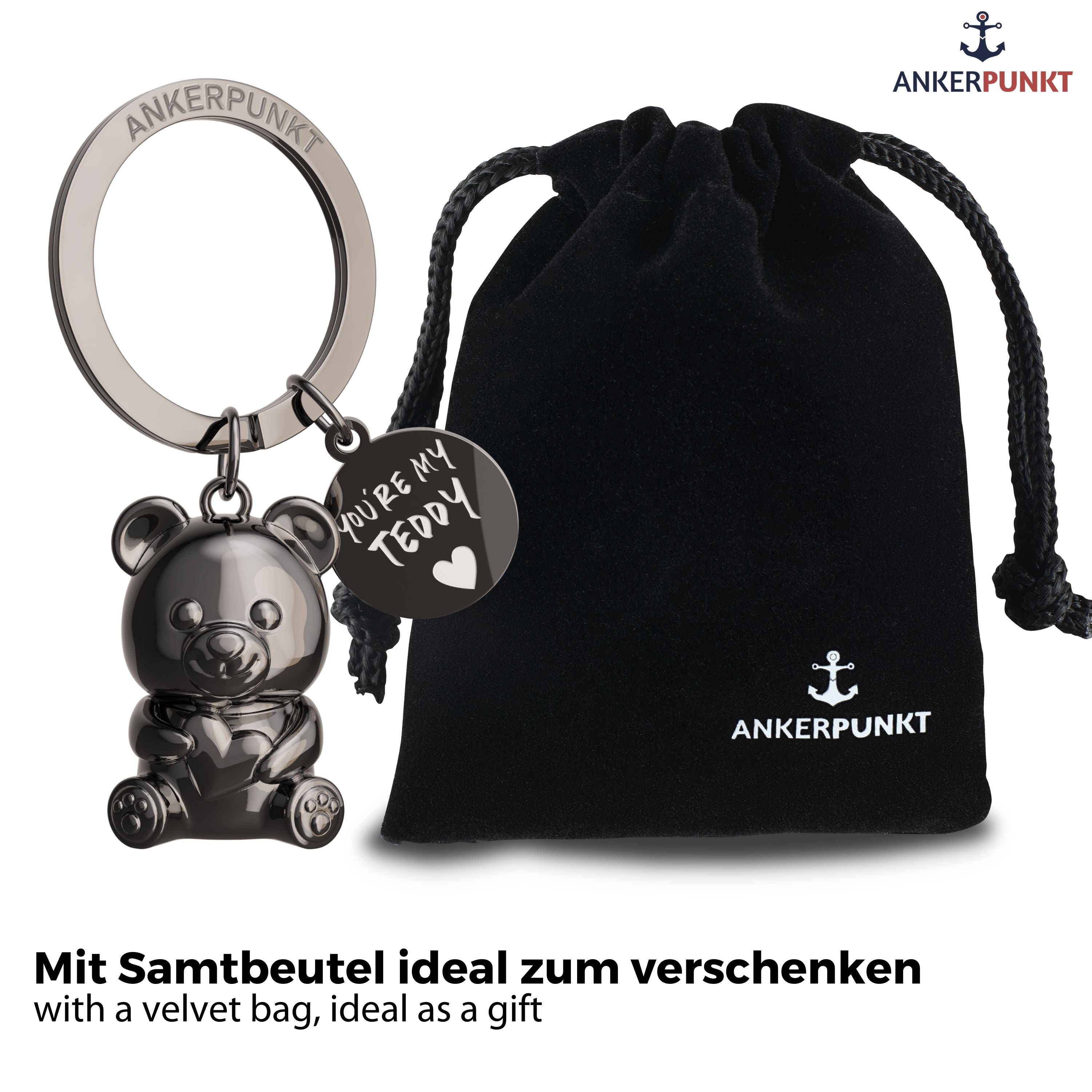 Teddybär Schlüsselanhänger in schwarz glänzend mit Anhängerplättchen mit Gravur "You're my Teddy", daneben ein Samtbeutel mit Ankerpunkt-Logo