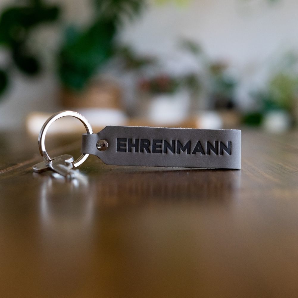 Schlüsselanhänger mit Gravur Ehrenmann in grau liegt auf Tisch
