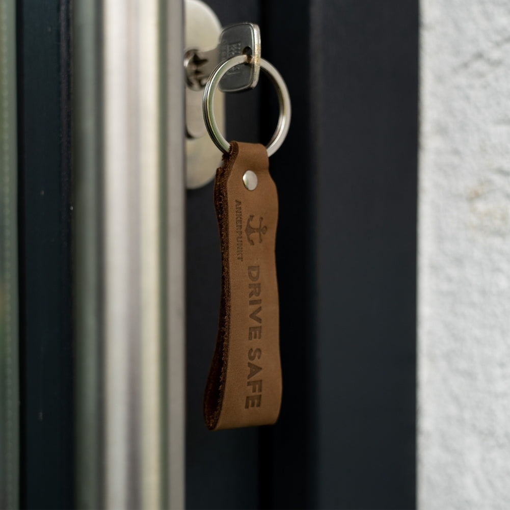 Schlüsselanhänger Drive Safe dunkelbraun im Türschloss hängend