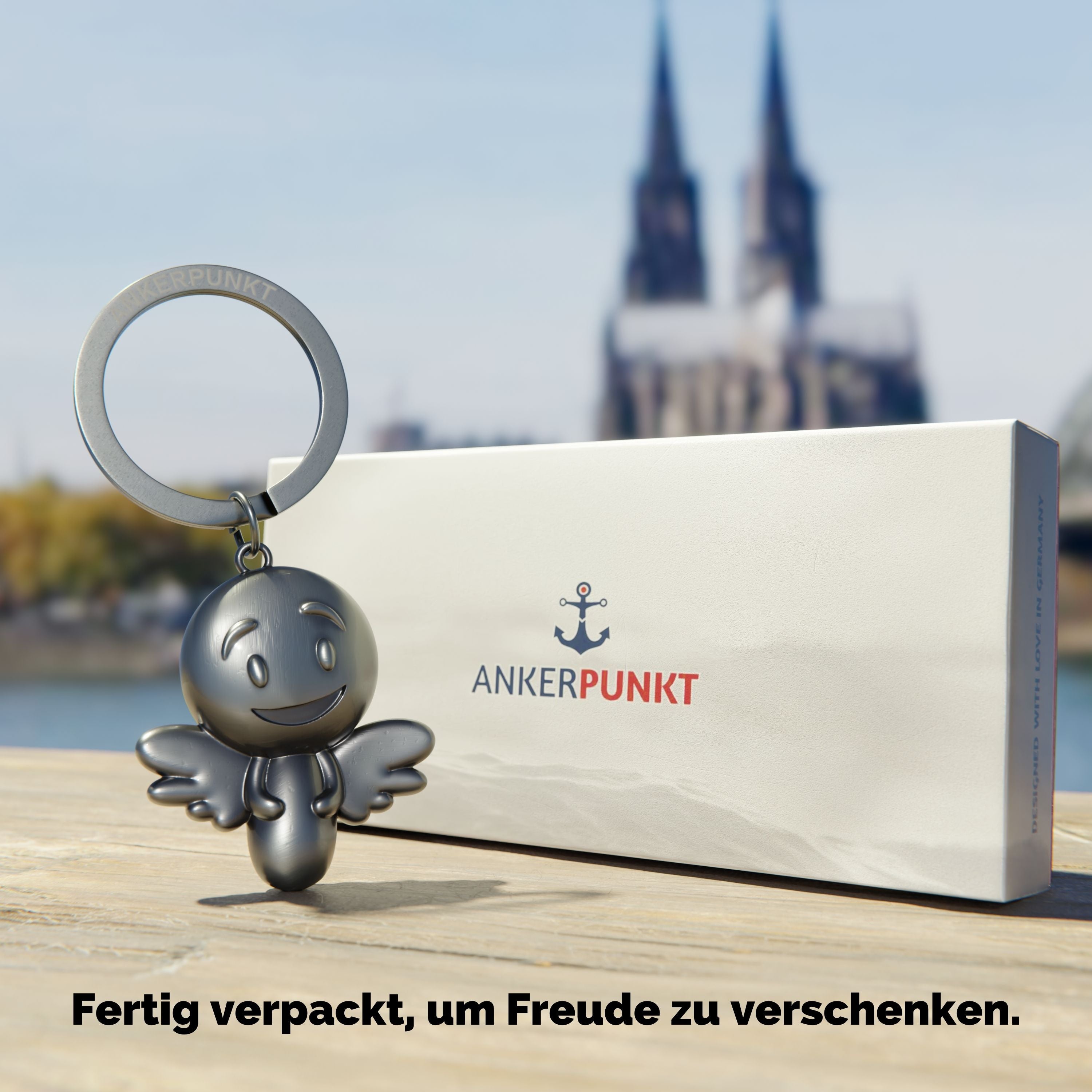 Schlüsselanhänger Engel silber vintage mit Verpackung am Rhein, im Hintergrund ist der Kölner Dom zu sehen