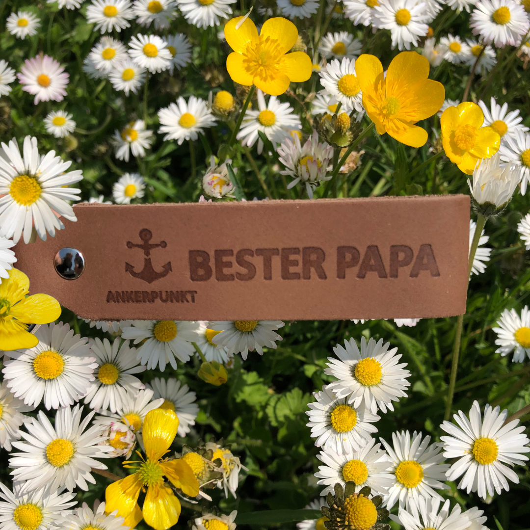 Schlüsselanhänger mit Gravur Bester Papa liegt auf Blumen auf